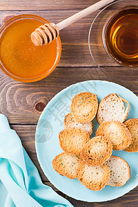 木制桌上盘子上的小面包面包烤面包 带蜂蜜的自制茶高清图片