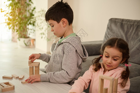 精细运动技能和注意力的发展 教育休闲 家庭消遣理念 专注于儿童用木块搭建结构 在家里的客厅里玩棋盘游戏背景图片