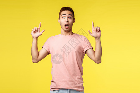 生活方式 人和暑假概念 穿着粉色 T 恤的亚洲男性惊讶 印象深刻 手指向上 张开嘴 惊讶而惊讶 展示新广告 酷产品情感手势技术男背景图片