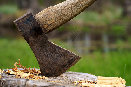 林务员木柄卡在树桩上的旧的生锈斧子 背景模糊 木原木堆积 森林本底碎木中大斧头记录器乐器金属木头日志切割刀刃林业工具工作背景