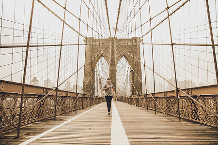 奔跑在布鲁克林桥上训练跑步赛跑者运动音乐运动员女性锻炼慢跑者城市背景图片