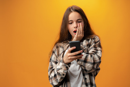使用智能手机微笑的年轻女孩的肖像女士青少年视频休闲装女性装置细胞衣服技术阅读背景图片