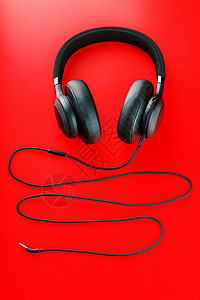 黑色耳机素材红色背景的无线黑耳机 从上方查看 用于游戏和听音乐音轨的近距离耳机打碟机白色帽子配饰工具娱乐电子产品技术听力立体声背景