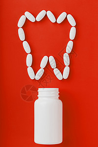 牙状粽子在红色背景上从白罐子里洒出一颗牙状的钙维他命矿物质疼痛疾病药品止痛药维生素处方医生制药抗生素背景