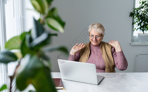 在家里或办公室工作的严肃成熟的老年妇女在笔记本电脑上观看培训网络研讨会 60 多岁的中年女商务人士在使用计算机技术时做笔记教学技背景图片