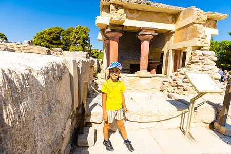 一个小女孩停下来 在克诺索斯米诺安宫墙壁上拍摄一张照片 希腊克里特历史性房子游客女孩观光岛屿历史地标旅行框架背景图片