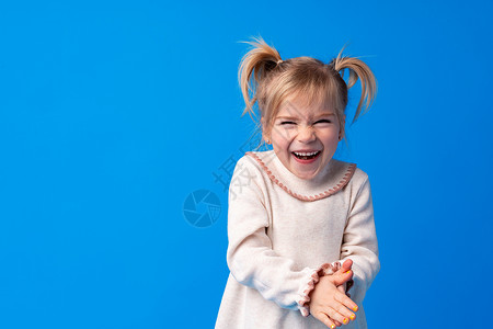 充满欢悦的迷人女孩在蓝色背景下微笑和笑容情感乐趣童年享受幸福卷曲幼儿园牙齿婴儿快乐背景