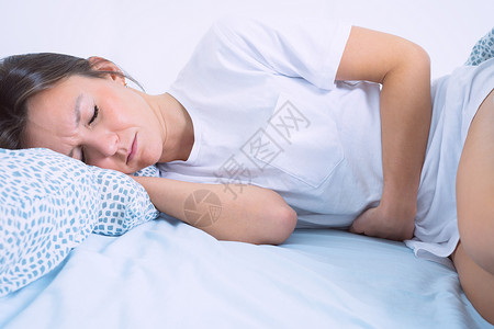 周期年轻女子躺在床上 患有妇科病 月经痛 胃痛或腹痛 月经期或 PMS背景