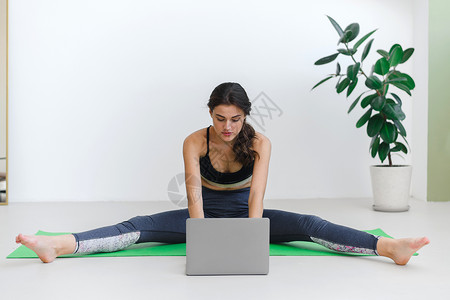 年轻妇女做伸展工作 在大流行病和隔离期间保持健康电脑氛围女子女士自由体操有氧运动网课笔记本在线客户背景图片