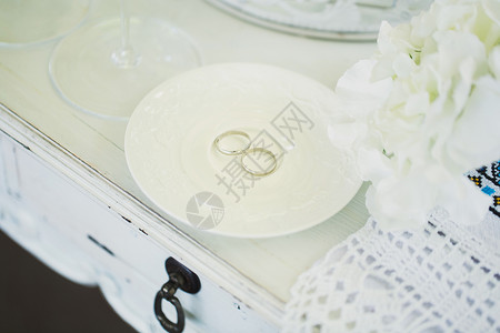 在一个陶瓷白碟上的婚环高清图片