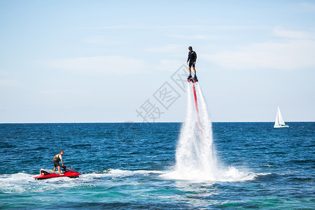 海洋飞翔板上的骑手会做困难的特技船只杂技喷射假期发动机爱好行动海滩空气闲暇背景图片