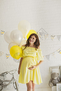 在演播室穿黄色礼服的漂亮孕妇孩子生活自行车气球母性身体父母男生成人女性背景图片