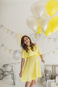 在演播室穿黄色礼服的漂亮孕妇产妇婴儿女孩成人家庭影楼气球怀孕裙子男生背景图片