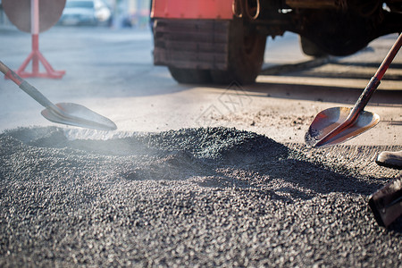 柏油碎石在公路修理工程期间 在机器上建造青年建筑师道路铺路路面运输工具振动施工建筑沥青柏油背景