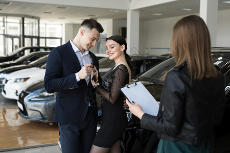 一对夫妇都乐意在与卖方的汽车经销商中购买一辆新车背景