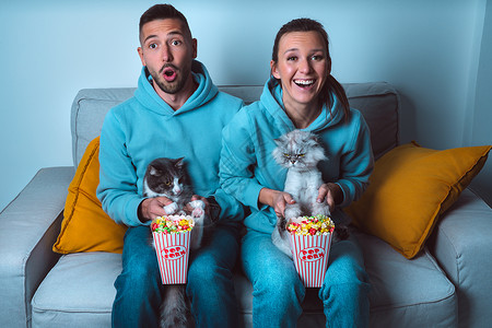 有爆米花和滑稽猫 坐在沙发上看喜剧电影 在家共度时光的快乐情侣背景图片