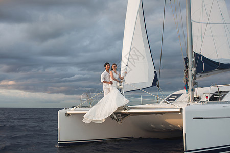 婚配情侣在游艇上拥抱新郎的美新娘男性女性假期男人面纱新娘婚姻双体甲板成人背景图片