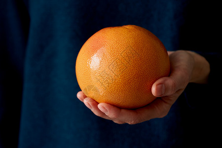 近亲手握着深底的全红亮柑橘子水果葡萄汁的女人背景图片