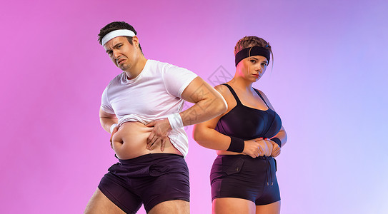 健身房里的胖男人和女人 身体积极和健身概念 一对恩爱的夫妻对他们在婚礼后体重增加的事实感到不高兴背景图片