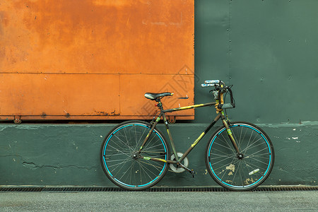 自行车锁一辆自行车在钢橙门前 有绿墙的仓库人行道橙子入口建筑学旅行运输金属绿化车轮潮人背景