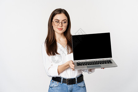 房地产宣传展架戴眼镜的年轻女青年显示笔记本电脑屏幕 在计算机 网站或商店展示宣传 站在白色背景上办公室职业女孩工人学生商务快乐工作人士管理人员背景