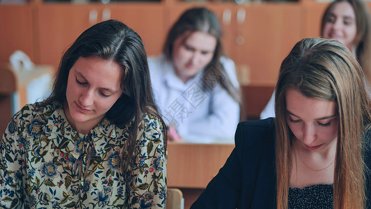 来岁是丰年上课时课桌边的班级11年级学生 是俄罗斯学校的学生考试女孩帮助知识课堂男性同学男生教育微笑背景