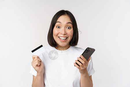 网上购物 快乐的亚洲女性使用信用卡和智能手机应用程序 通过手机在网站上付款 白色背景工作室送货企业家银行互联网女朋友横幅女孩购物背景图片