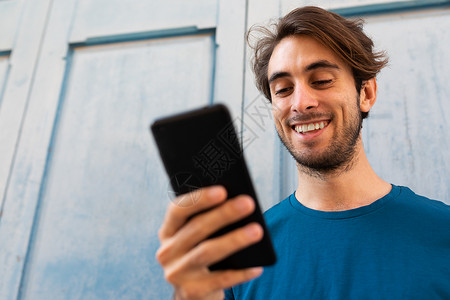利用户外手机拍摄的年轻黑人男子微笑近距离肖像 复制空间 有选择地关注面部背景图片
