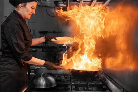 厨房用火厨房的女厨师烹饪 在商业厨房用蔬菜煮火烧烤鸡尾酒平底锅食物炒锅搅拌餐厅火炉洋葱火焰油炸胡椒背景
