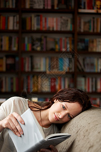 在她自己的世界里 一个有魅力的年轻女人在沙发上放松 带着一本书 复制空间背景图片