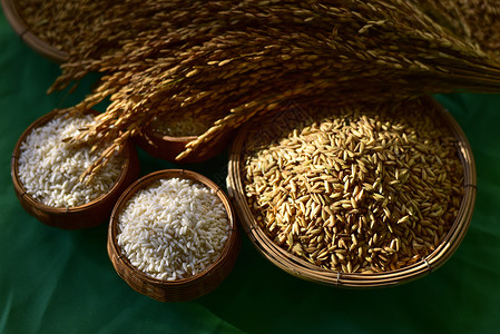 木筐里的谷物放在绿布背景上的水稻和大米 农业的想法 选择性的焦点 木碗中白米和稻谷的顶视图 特写背景图片