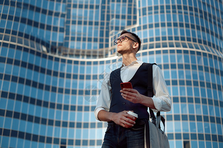 手机上城市建筑年轻人在读他的智能手机上的留言背景