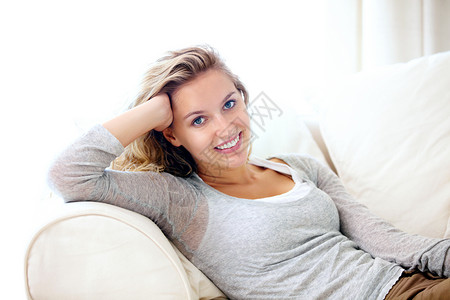 在沙发上平静自信 一位年轻女人的肖像 她在家里在沙发上放松背景图片