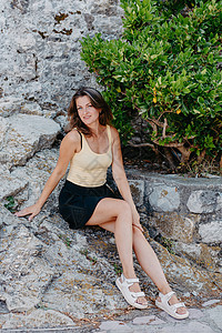 美丽的女孩坐在布德瓦老城的石墙上 女孩坐在石栏杆上 布德瓦 黑山天空旅行女性景观堡垒裙子岩石游客蓝色旅游背景