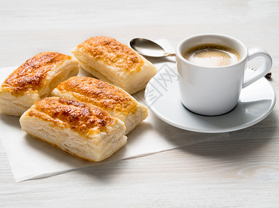 咖啡杯勺子早餐吃着新鲜的松饼卷和白木桌上的咖啡杯 清晨糕点咖啡食物羊皮纸化合物日光白色桌子麸质烘烤背景
