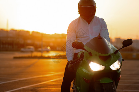 酷哥骑摩托车对抗日落天空天空大男子阳光运动主义沥青城市男性爱好背光背景图片