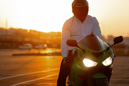 酷哥骑摩托车对抗日落天空爱好阳光头盔车辆大灯运动天空大男子自由背光背景图片