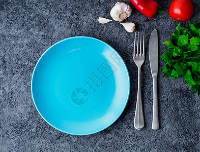 清空的蓝色亮板 叉子和刀 在灰色混凝土背景上 最上面的视野背景图片
