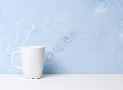 白杯茶或咖啡在白色桌子上 对面是浅蓝色混凝土墙背景图片