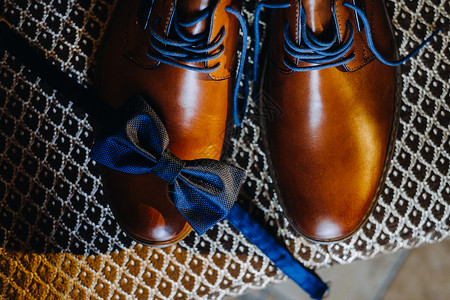 棕色丝带新郎早 棕色男人鞋上的蓝色领结 紧贴着蓝领带背景