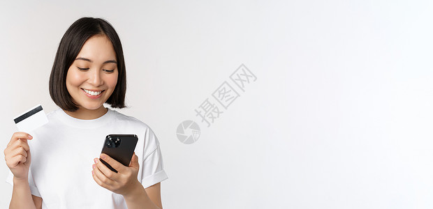 网上购物 快乐的亚洲女性使用信用卡和智能手机应用程序 通过手机在网站上付款 白色背景女孩女士帐户银行细胞银行业工作室互联网学生送背景图片