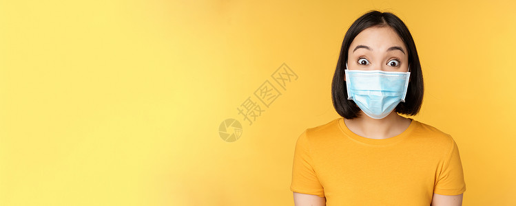 Covid19和医疗概念 近距离地拍下脸面面具的亚洲女性肖像 在黄色背景上站立 对新闻感到惊讶和惊异保健商业企业家大学女朋友情绪背景图片