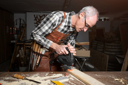 王动摄影木匠正在木工车间用电动曲线锯机锯木板 木工 DIY 概念木头木材摄影材料工作男人机器职业工艺跳汰机背景