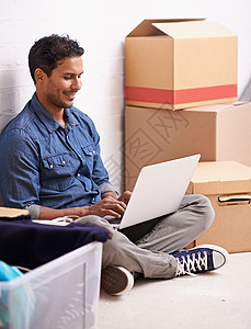 搬家日 一个年轻人在两箱之间用笔记本电脑工作成人学习房子裁剪互联网冲浪幸福盒子技术男性背景图片