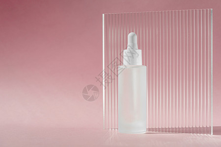 白色透明瓶中含有胶原蛋白和肽的血清油 粉红色背景上带有滴管 带有丙烯酸肋板 护肤治疗护肤样机包装液体化妆品背景图片