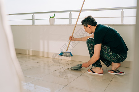 男人用拖把擦地板 看门人清洗脏地板 阳光明媚的日子里 男人正在擦阳台 做家务的人 小伙子用清洁设备给表面除尘工具抹布家务卫生房子图片
