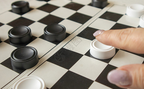 女人的手在黑白竞技场上移动一个白棋手 爱好和家庭游戏的概念女性知识分子宏观成功战略逻辑男性手指娱乐思维背景图片