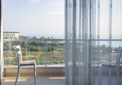 在一个露天的微小阳台上 俯视海面 有一个空椅子地面房子地毯假期阳光丛林公寓地板财产房间背景图片