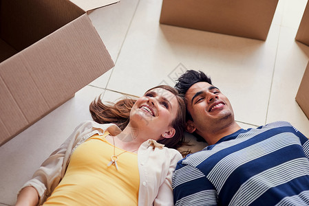 拍到一对年轻夫妇躺在地上 从搬进新家里休息了一会儿的镜头 - 是的背景图片
