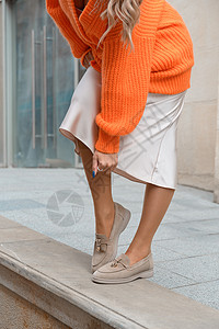 穿着橙色毛衣和在街上露面的米粉服装的时装妇女肖像橙子压痛女孩情感诱惑裙子金发女性喜悦成人背景